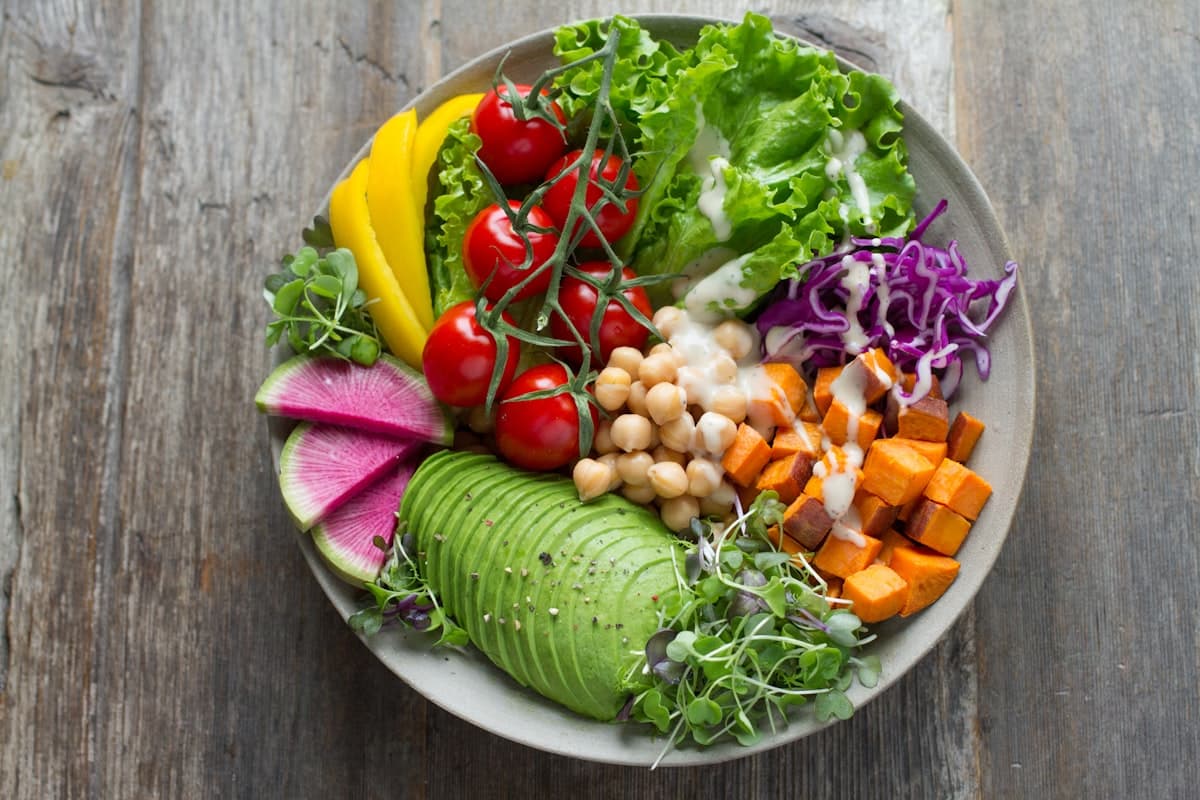 A fresh bowl of colorful vegetables and greens on a wooden table
